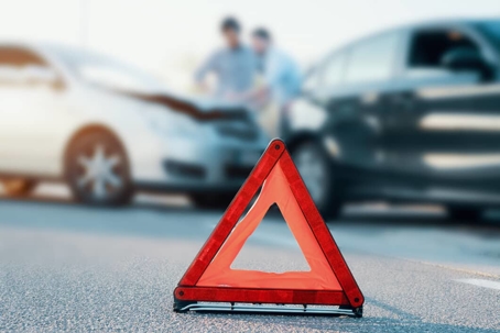 Orange warning cone next to two damaged cars